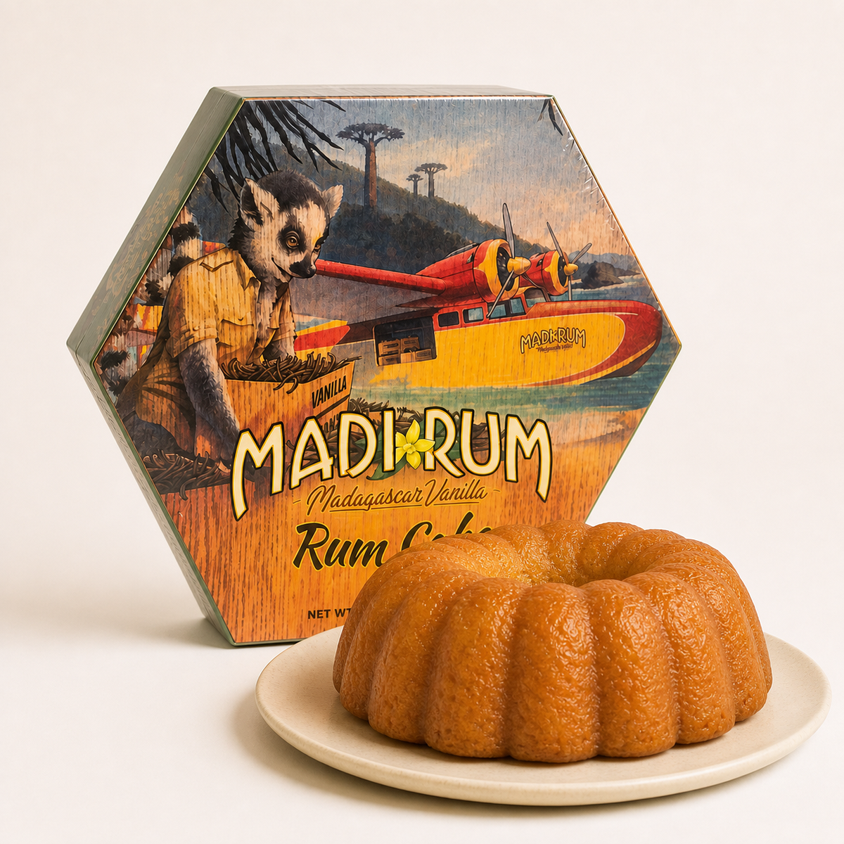 Madi Rum Madagascar Vanilla Rum Cake in its illustrated hexagonal box, with the ring-shaped cake on a plate beside it