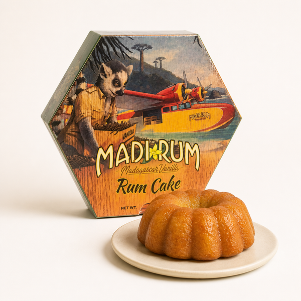 The smaller Madi Rum Madagascar Vanilla Rum Cake in its illustrated hexagonal box, with the ring-shaped cake on a plate beside it